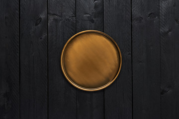 Top view of golden stylish serving plate on black wooden table with copy space.