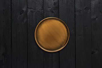 Fototapeta premium Top view of golden stylish serving plate on black wooden table with copy space.