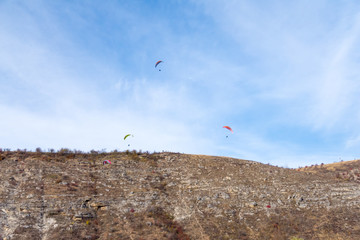 Fototapeta na wymiar para-gliders on blue autumn sky flying near a cliff