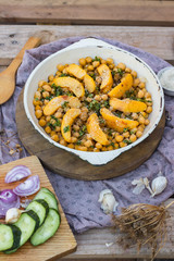 Baked chickpea with quince in cast iron skillet, frying pan with wooden spatula on it. Vegan vegetarian lunch, paleo diet, healthy dinner served with salad and vegetables on table. Top view