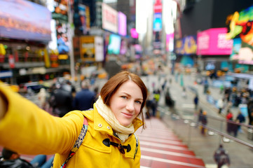 Happy young woman tourist sightseeing at Times Square in New York City. Female traveler enjoying...