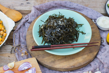 Traditional asian laminaria seaweed chuka salad served garlic, sesame oil, sesame seeds on plate with chopsticks. Vegan vegetarian lunch, paleo diet, healthy food