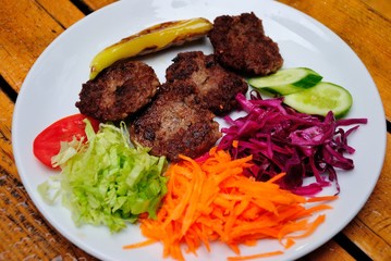 Grilled Akchaabat meatballs (kofte), served with grilled pepper, fresh tomatoes, cucumber, carrot, red cabbage and a salad in Trabzon, Turkey