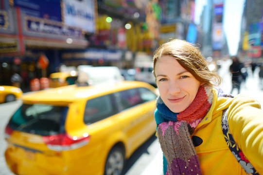 Happy young woman tourist sightseeing at Times Square in New York City. Female traveler enjoying view of downtown Manhattan.