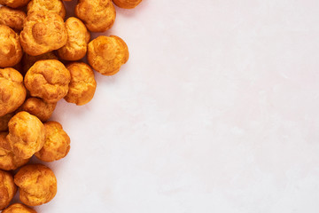 Bunch of fresh cream puff cakes on rose background with copy space. Top view.