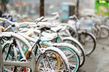 Fototapeta na wymiar Row of old bicycles covered with snow after massive snowfall in New York City at wintertime.