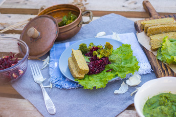 Vegan, vegetarian lunch, dinner with raw flax sunflower seeds bread slices, avocado spinach dip sauce, fresh beetroot garlic salad and steamed, cooked broccoli in pot. Healthy food, paleo diet