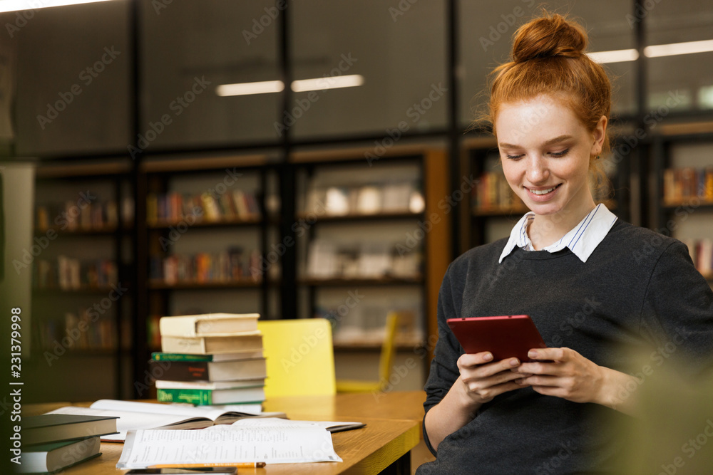 Wall mural Smiling red haired teenage girl studying