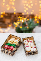 Variety of sweet macaroons in carton box. Cookie in the form of a snowman. Merry Christmas card. New year mood. lights of garland bulbs