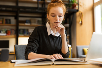 Pretty red haired teenage girl using laptop computer