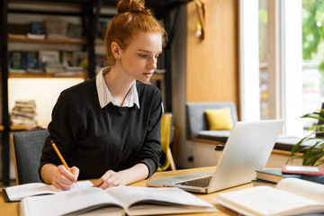 Lovely red haired teenage girl using laptop computer