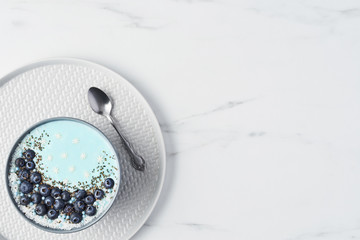Top view of blue yogurt smoothie bowl made with blueberry, coconut flour, chia seeds and sugar...