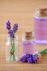 Obraz na płótnie Canvas lavender oil in glass bottles and fresh lavender flowers on wooden background