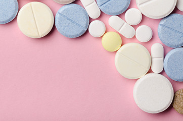 multi-colored tablets of different shapes close-up on a pink background