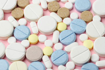 multi-colored tablets of different shapes close-up on a pink background