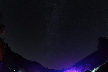 Night starry sky above the forest in the mountains