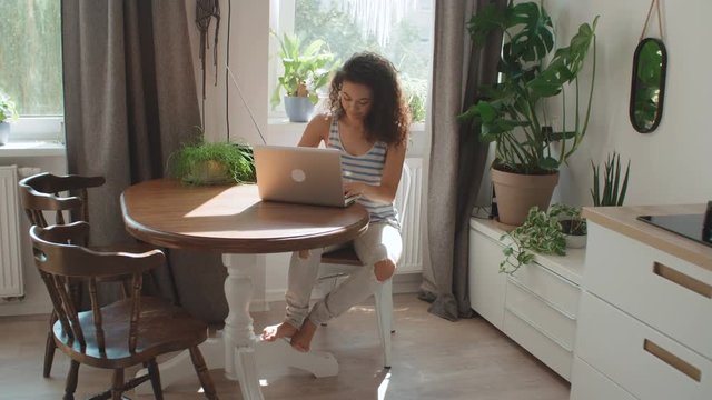 Charming young woman typing on laptop computer at home.