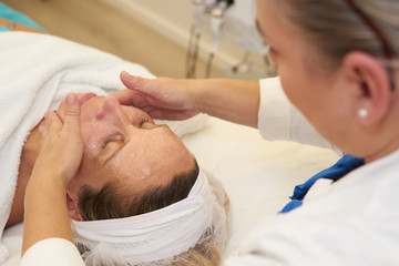 Obraz na płótnie Canvas cosmetician giving facial massage to female customer