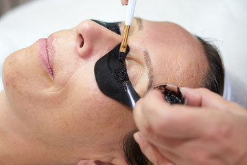 cosmetician painting eyelashes with brush