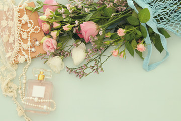 fresh vintage perfume bottle next to aromatic flowers on wooden table.