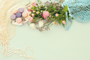 plate of macaroons over wooden table and flowers.