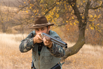 Fototapeta premium Hunter with a hat and a gun in search of prey in the steppe