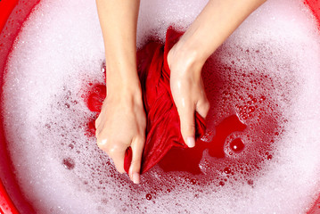 Fototapeta premium Women washing color clothes in basin enemale powdered detergent, top view