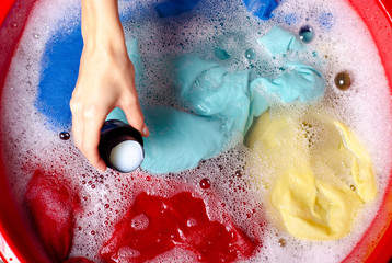Fototapeta premium Women washing color clothes in basin enemale powdered detergent liquid laundry gel, top view
