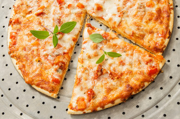 Freshly baked pizza decorated with green basil leaves