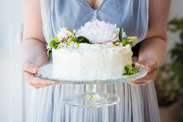 Obraz na płótnie Canvas Woman holding birthday Cake decorate with flowers on a glass stand. Celebration concept. Trendy layer cake