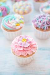 Many sweet birthday cupcakes with flowers and butter cream