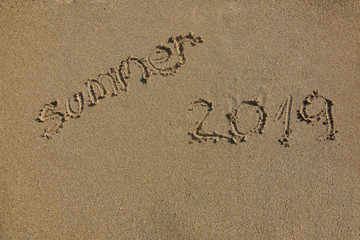 Summer vacation concept. Summer 2019 written on wet sand at the beach