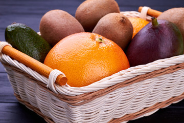 Close up wicker basket with tropical fruits. Tasty exotic fruits in basket. Vegetarian food concept.