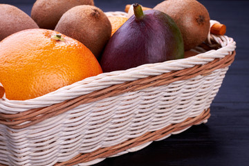 Composition with assorted fruits in wicker basket. Tasty organic fruits in basket close up. Exotic agriculture concept.