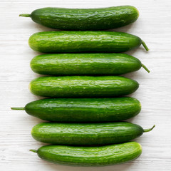 Flat lay of raw organic green cucumbers on white wooden surface. Top view, from above, overhead. Close-up.