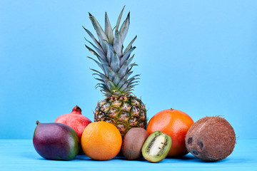 Composition of fresh tropical fruits. Assortment of ripe exotic fruits on blue background. Healthy nutritious diet.
