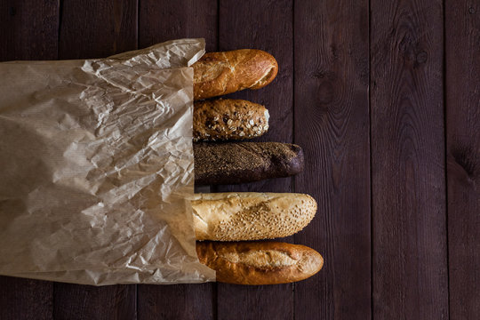 baguettes in paper bags on wooden table, top view. Copy space.
