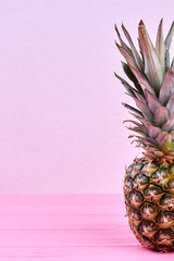 Whole fresh pineapple and copy space. Green organic ananas on pink wooden background and text space, cropped image.