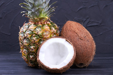 Fresh pineapple and coconuts on dark background. Composition from whole pineapple, whole coconut...