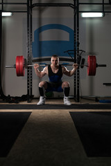 Fototapeta na wymiar Powerlifter Using Barbell Exercising Legs Inside Gym