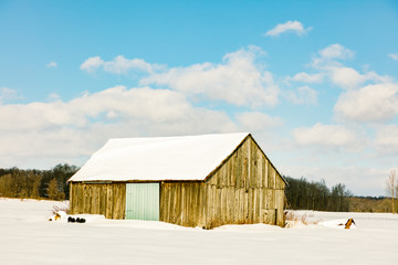 Antique barn in rural Quebec Canada in a snowy seasonal background.
