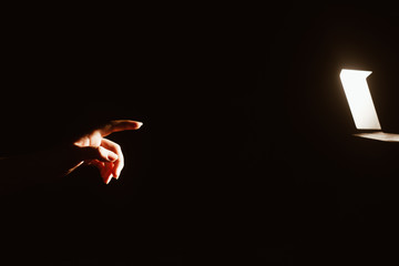 girl reaching for the light of the lantern, wooman in a dark room. illuminated hands