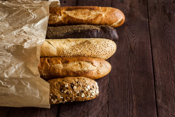 Various baked breads and baguettes on rustic wooden table. Close up