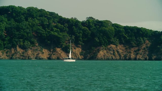 Sailboat bobs past the cliffs of Angel Island in SF Waters. View from Tiburon