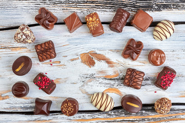 Frame from chocolate candies on wooden background. Mixed chocolate candies on vintage wood and copy space. Sweet tasty background.