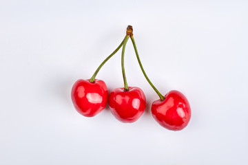 Obraz na płótnie Canvas Three ripe cherries isolated on white. Studio shot of red organic cherries.