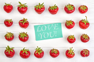Valentines Day background with fresh strawberries. Red sweet strawberries and turquoise card with text love you. Happy Valentines Day.