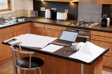 Working from home paperwork laptop PC on table in kitchen