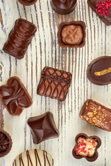 Wooden background with assorted chocolate candies. Top view on various chocolate sweets on wooden background.