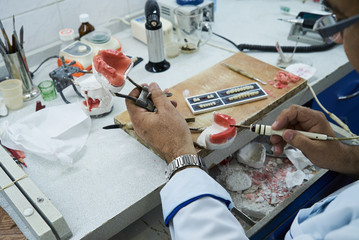 Dental technician or dentist working with tooth dentures in his laboratory, close-up
